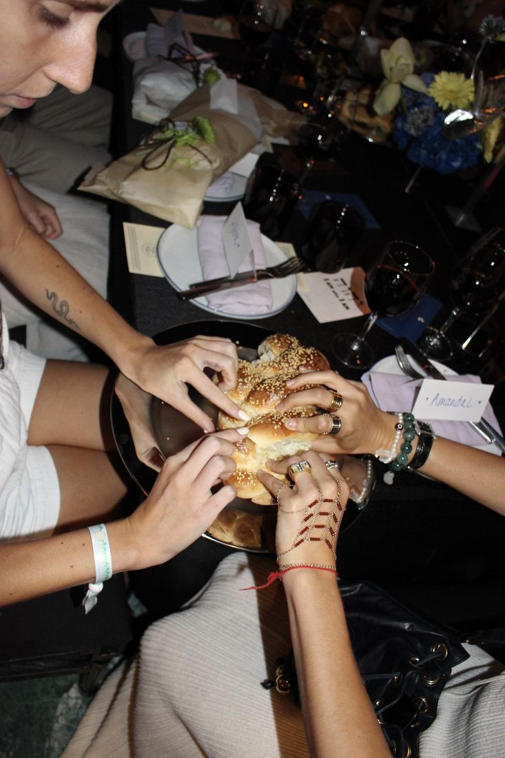 Friends tearing into a sesame challah together